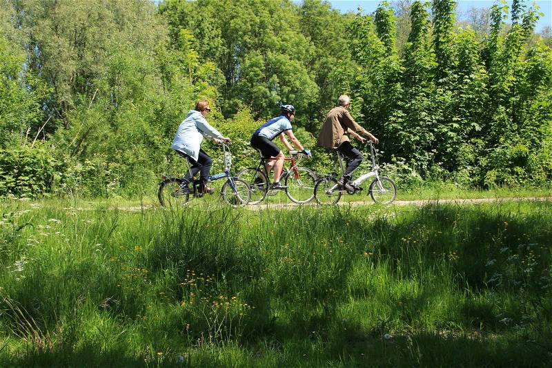 Couple, man and wife, and a cycler in sportswear cycling over the bike path in the park in spring, stock photo