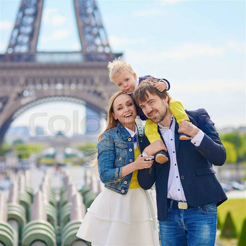 Happy family of three having fun together in Paris near the Eiffel tower, stock photo