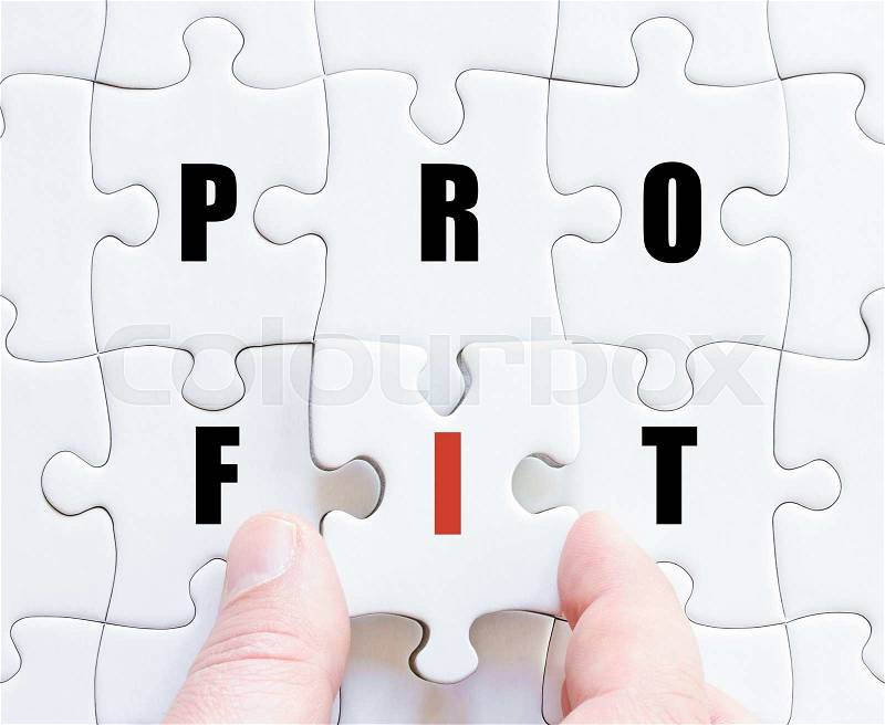 Hand of a business man completing the puzzle with the last missing piece.Concept image of puzzle board with motivational word PROFIT, stock photo