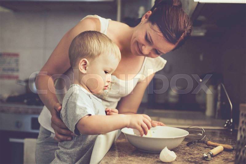 Mom with her 2 years old child cooking holiday pie in the kitchen to Mothers day, casual lifestyle photo series in real life interior, stock photo