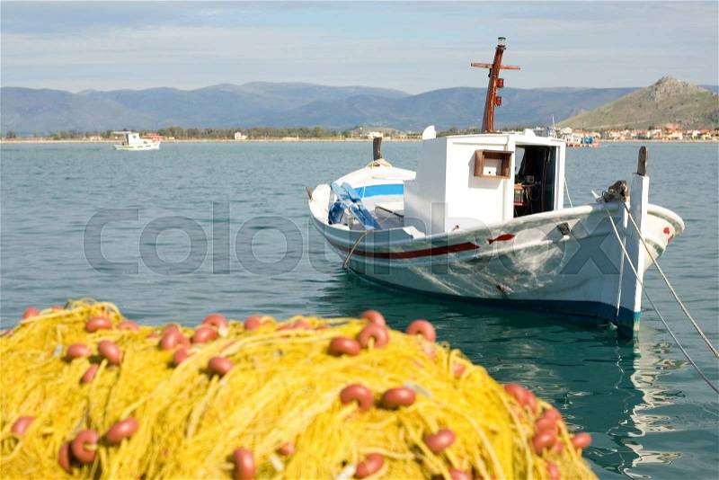End of fishing day. White boat and yellow fishing net with clear blue sea, stock photo
