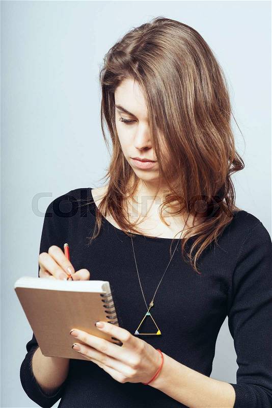 Woman writes in a notebook, stock photo