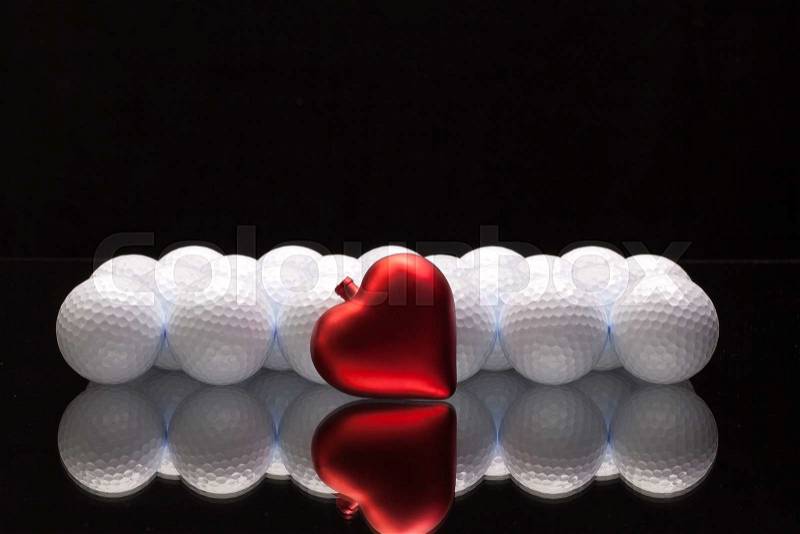 White golf balls and red heart on a glass plate, stock photo