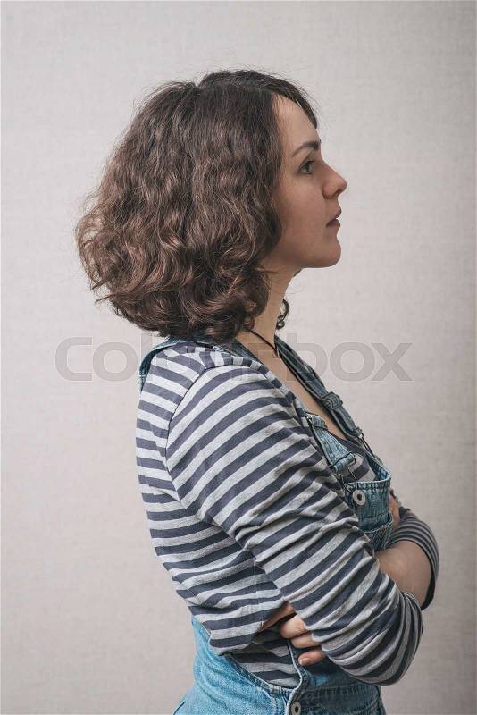 Woman folded her arms and turned away, dressed in overalls, stock photo