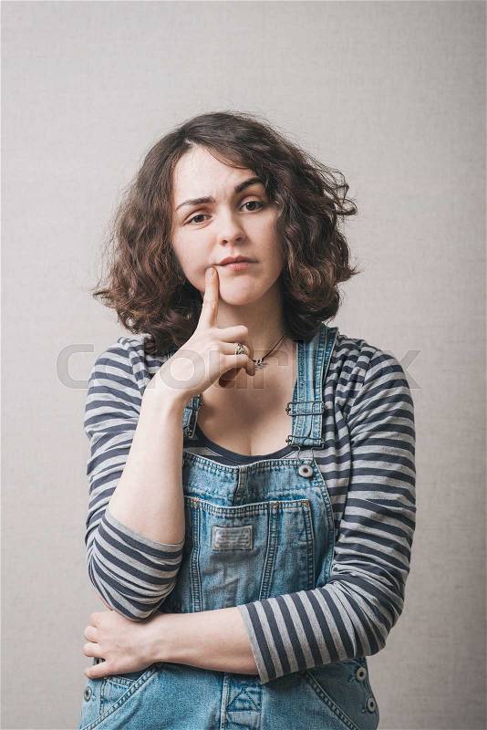 Woman remembers something, dressed in overalls, stock photo
