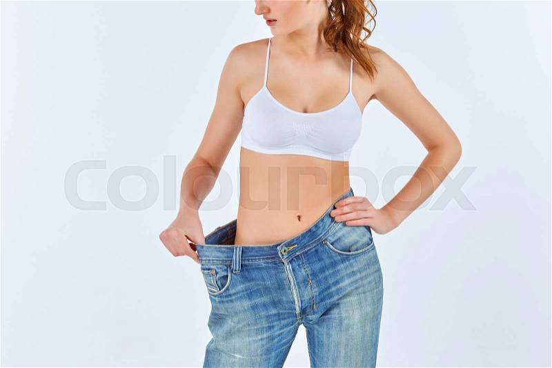 Woman became skinny and wearing old jeans on white background. concept of healthy lifestyle and beauty, stock photo