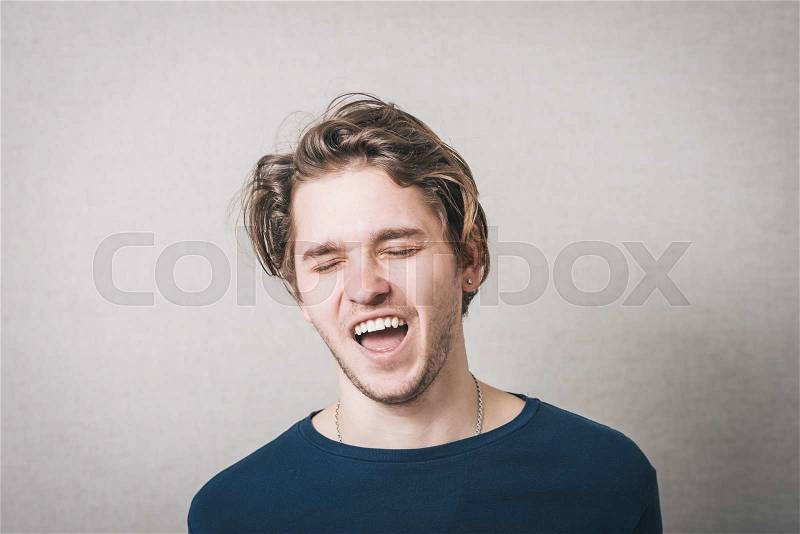 The man laughs. Gray background, stock photo