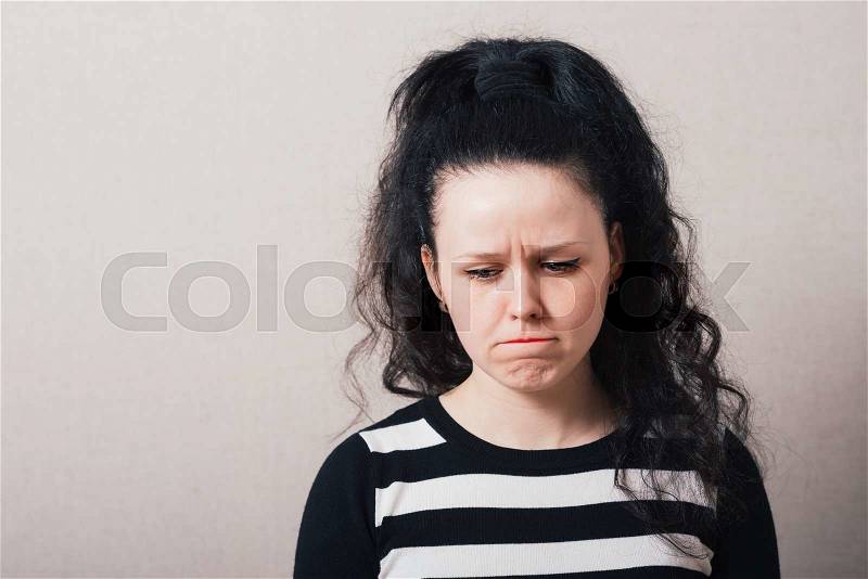 Woman sad, offended. Gray background, stock photo