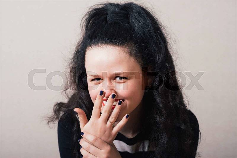 Woman laughing covering his face. Gray background, stock photo