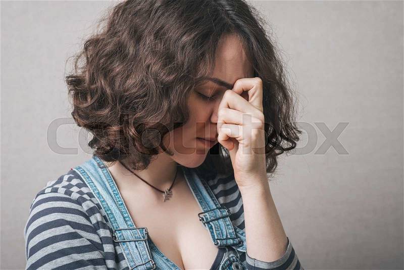 Woman sad, saddened, bowed her head. Gray background, stock photo