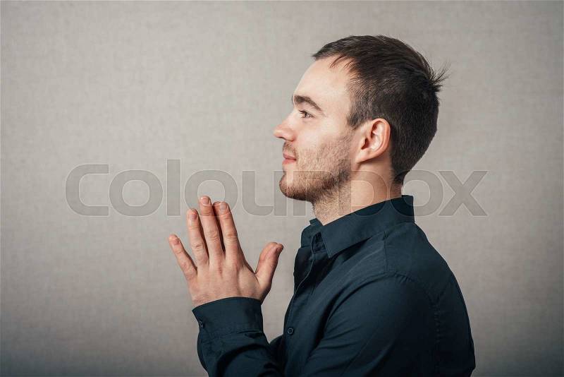 A man prays. On a gray background, stock photo