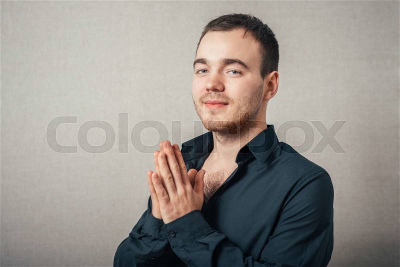 A man prays. On a gray background, stock photo