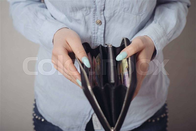 Close-up of women\'s purse in his hands. On a gray background, stock photo