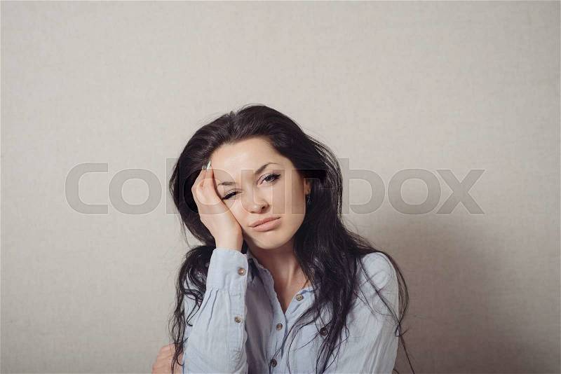 Woman bored, tired. On a gray background, stock photo