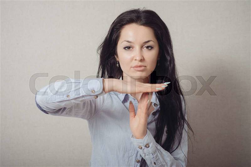 Woman showing a stop, can not be, a timeout. On a gray background, stock photo
