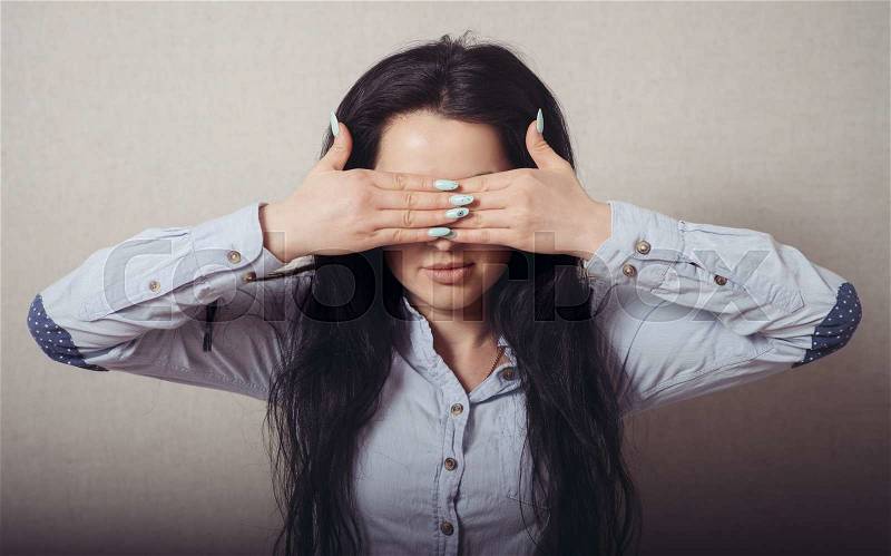 The woman closed eyes with her hands. On a gray background, stock photo