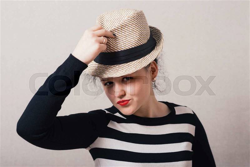Woman takes off his hat and clothes. Gray background, stock photo