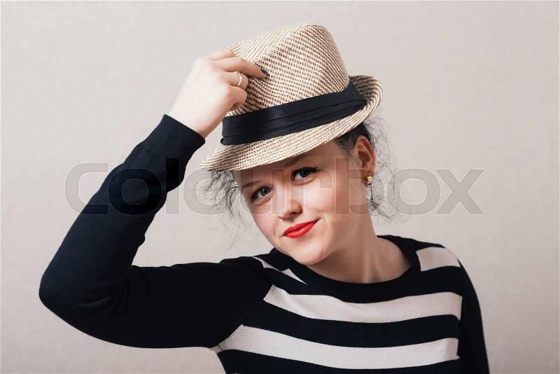 Woman takes off his hat and clothes. Gray background, stock photo
