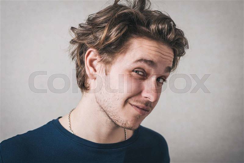 Man unhappy looking at the camera. Gray background, stock photo