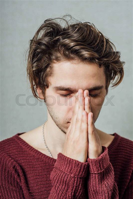 A man prays. Gray background, stock photo