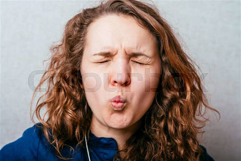 Curly woman unhappy wrinkled face. Gray background, stock photo