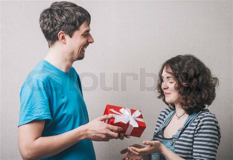Valentine Gift. Happy Young Couple with Valentine's Day Present. Happy Man giving a gift to his Girlfriend. Holiday, stock photo