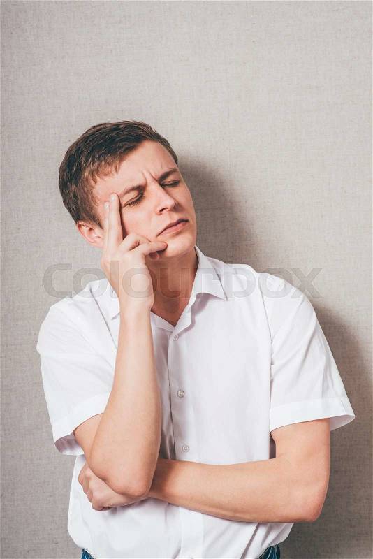 Young guy thinks his finger to his temple, stock photo