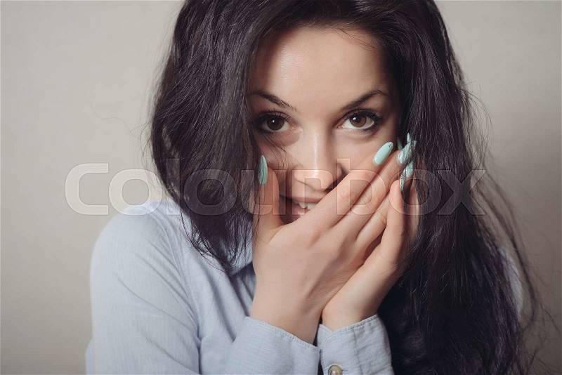 Excited woman happy smile cover her mouth by hand palm young attractive girl portrait, looking at camera smiling isolated over gray background, stock photo