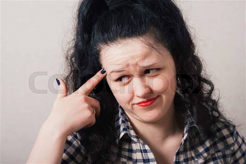 Young woman thinks his finger to his temple, stock photo