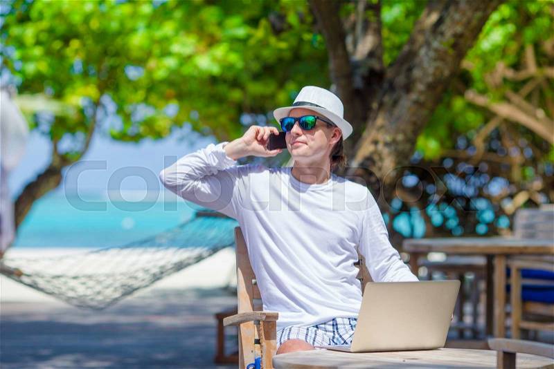 Young man calling by cell phone in outdoor cafe, stock photo