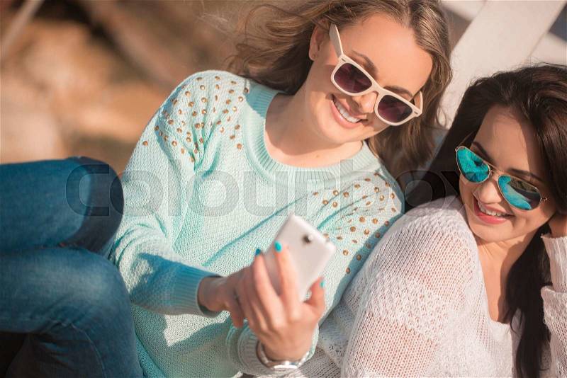 Two girls resting on the autumn beach, stock photo