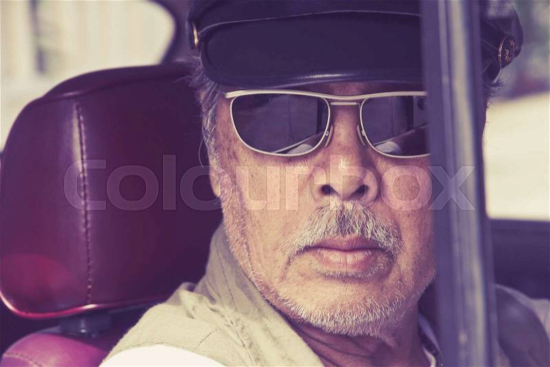 Older man with glasses driving a car, stock photo