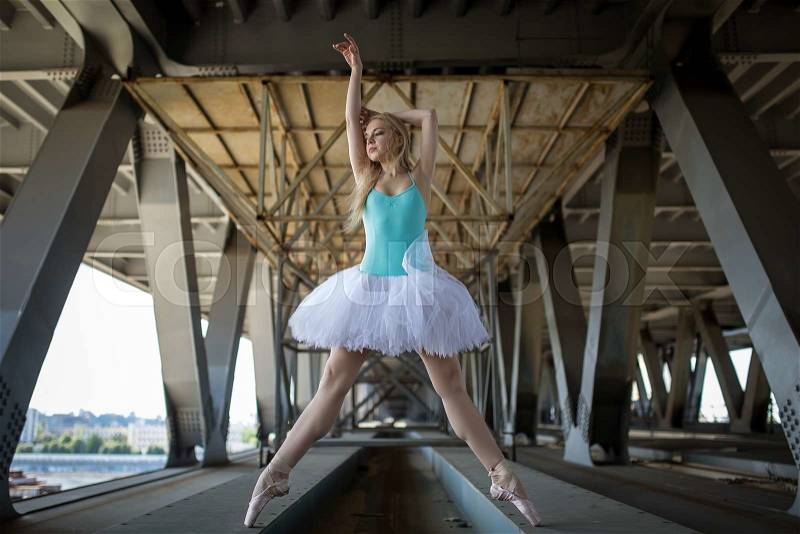 Graceful ballerina in white tutu in the industrial background of the bridge, stock photo