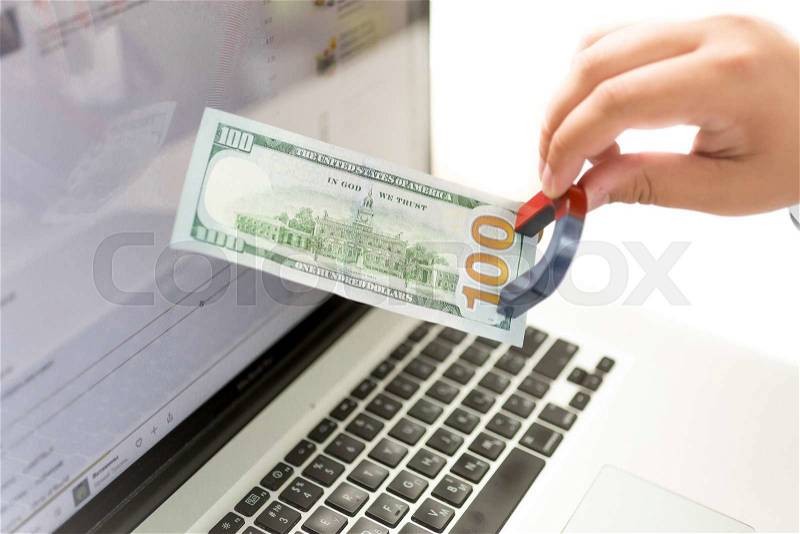 Closeup isolated money of man pulling money from laptop with magnet, stock photo