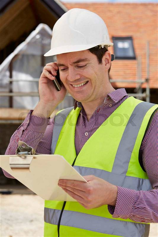 Architect On Building Site Using Mobile Phone, stock photo