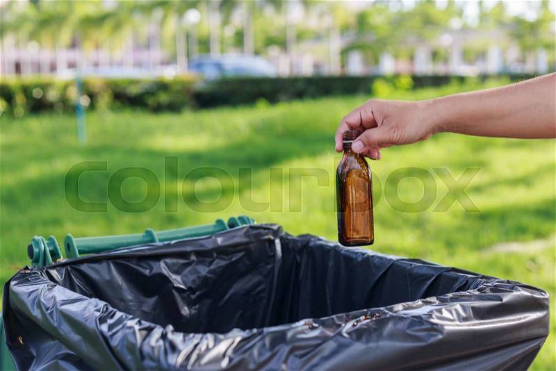 Close up hand throwing empty glass bottle into the trash, stock photo
