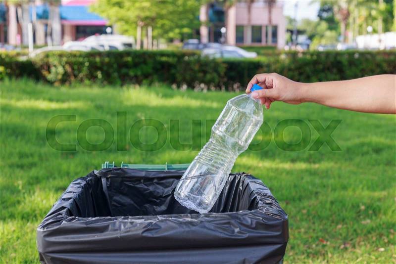 Close up hand throwing empty plastic bottle into the trash, stock photo