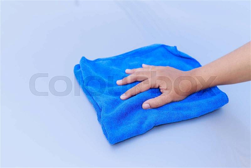 Close up woman hand with blue microfiber cloth cleaning the car, stock photo