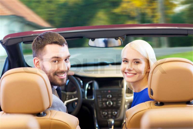 Drive, auto transport and people concept - close up of happy couple driving in cabriolet car from back over city street background, stock photo
