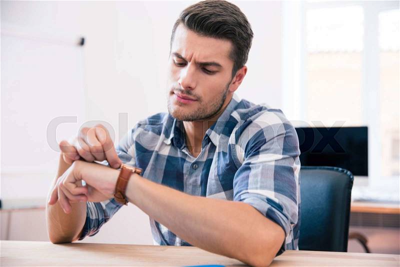 Handsome young businessman in casual cloth looking on wrist watch, stock photo