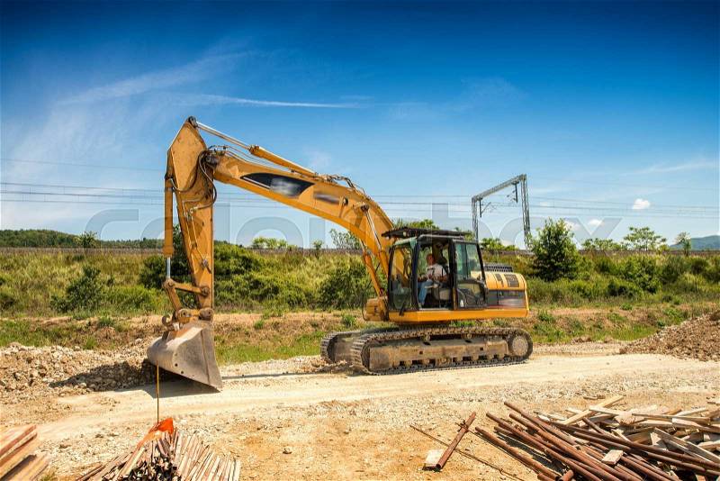 Big excavator on new construction site, in the background the blue sky and sun, stock photo