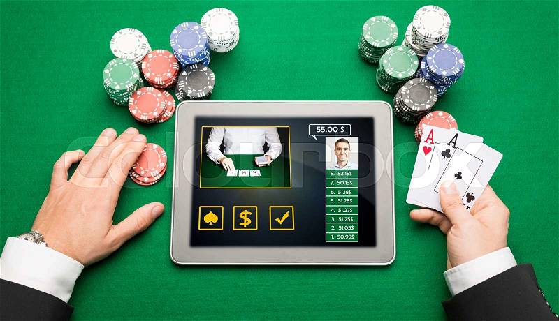 Casino, online gambling, technology and people concept - close up of poker player hands with playing cards, tablet pc computer and chips at green casino table, stock photo