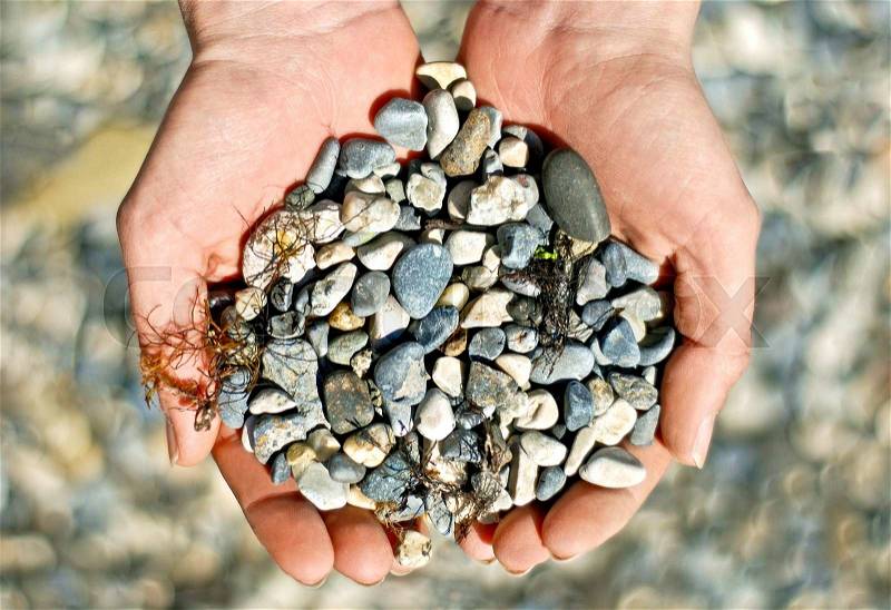 Handful of stones in hands, stock photo