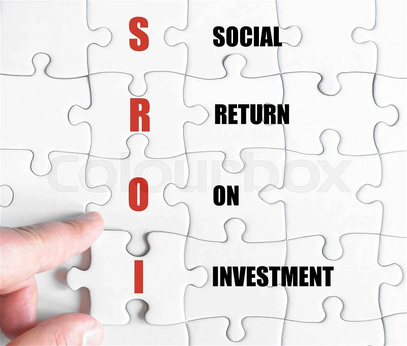 Hand of a business man completing the puzzle with the last missing piece.Concept image of Business Acronym SROI as Social Return On Investment, stock photo