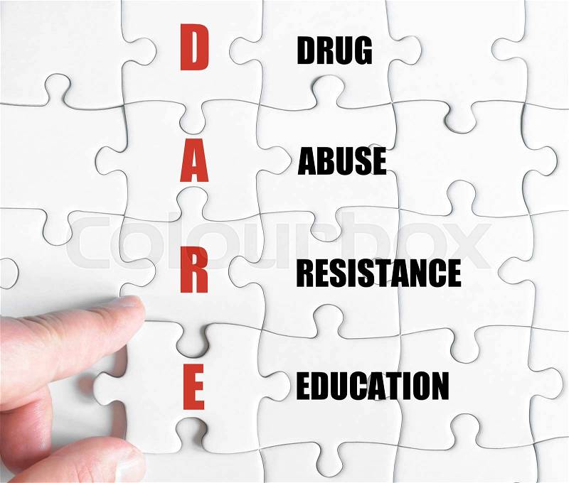 Hand of a business man completing the puzzle with the last missing piece.Concept image of Business Acronym DARE as Drug Abuse Resistance Education, stock photo