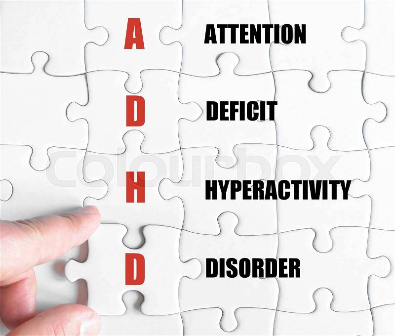 Hand of a business man completing the puzzle with the last missing piece.Concept image of Business Acronym ADHD as Attention Deficit Hyperactivity Disorder, stock photo