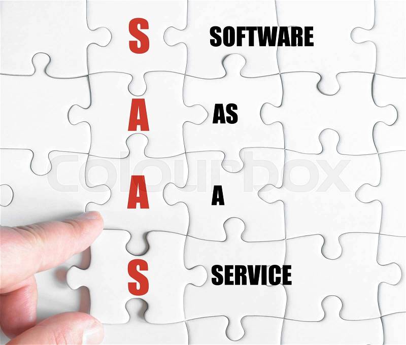 Hand of a business man completing the puzzle with the last missing piece.Concept image of Business Acronym SAAS as Software As A Service, stock photo