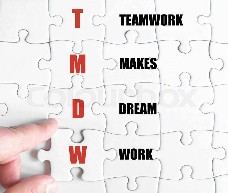 Hand of a business man completing the puzzle with the last missing piece.Concept image of Business Acronym TMDW as TeamWork Makes Dream Work, stock photo