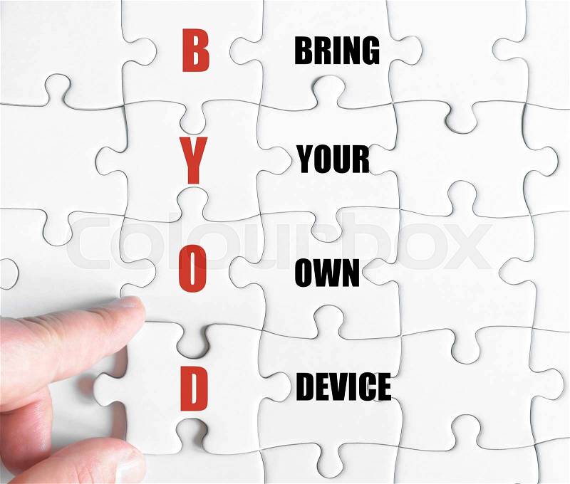 Hand of a business man completing the puzzle with the last missing piece.Concept image of Business Acronym BYOD as Bring Your Own Device, stock photo