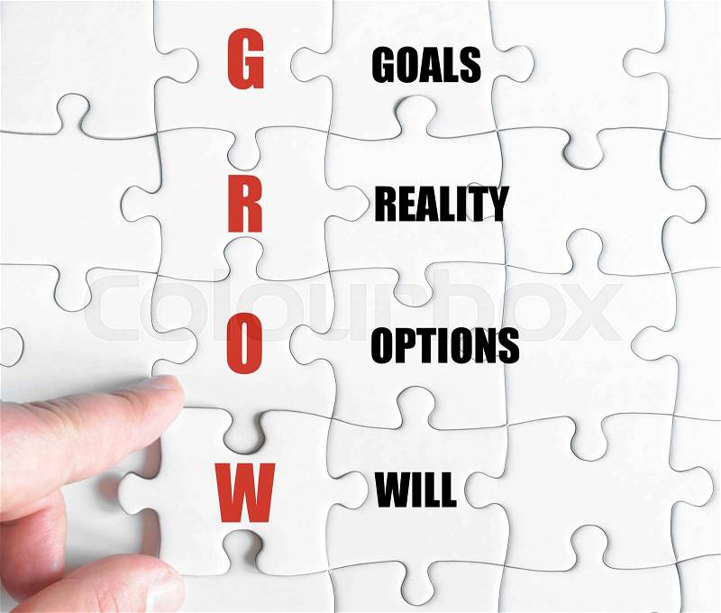 Hand of a business man completing the puzzle with the last missing piece.Concept image of Business Acronym GROW as Goals Reality Options Will, stock photo